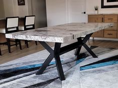 a dining room table with chairs and a rug on the floor in front of it