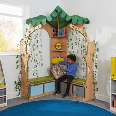 a child sitting on a bench reading a book in a room with bookshelves