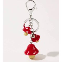 two red mushrooms are hanging from a metal keychain on a white background,