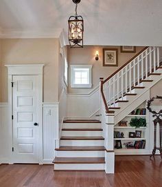 the stairs in this house are made of wood and have white railings with two lanterns hanging from them