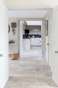 an open hallway leading to a kitchen and dining room with white walls, tile flooring and cabinets