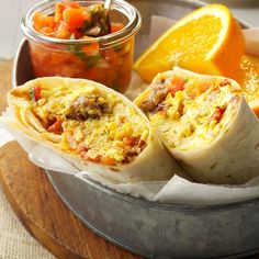 two burritos are sitting on a plate next to some fruit