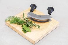 a knife and some herbs on a cutting board with a knife sharpener next to it