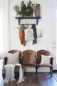 two wooden chairs sitting next to each other in front of a wall with pictures on it