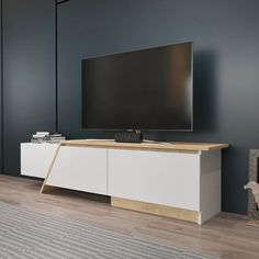 a flat screen tv sitting on top of a white cabinet in front of a gray wall