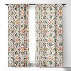 a window curtain with an orange and green flower pattern on it, in front of a white wall