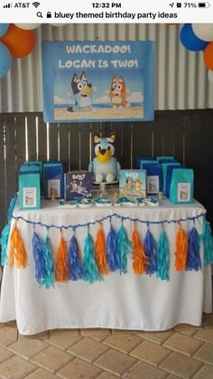 the birthday party table is decorated with blue, orange and white streamers