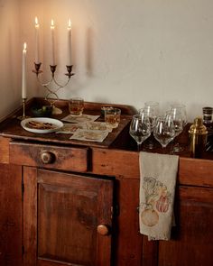 a table with wine glasses, plates and napkins on it in front of candles