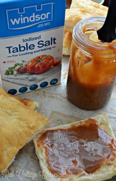 some food is sitting on a table with a jar of sauce next to it and another item in the background