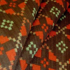 an orange and brown patterned blanket with red, white, and green designs on it