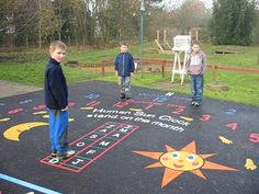 three children are standing in front of a chalkboard with numbers and stars on it