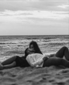 black and white photograph of two people laying on the beach