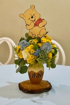 a winnie the pooh flower arrangement in a vase on top of a wooden stump