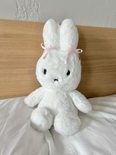 a white stuffed rabbit sitting on top of a bed