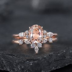 an oval morganite and diamond engagement ring on top of a black rock with white diamonds