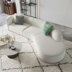 a white couch sitting on top of a rug in a living room next to a table