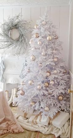 a white christmas tree with gold and silver ornaments on it in the corner of a room