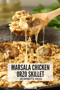 a skillet filled with masala chicken orzo skillet is being lifted from the skillet by a wooden spoon