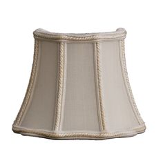 a white lamp shade with braiding on the bottom and beige trimming around it