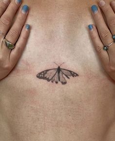 a woman's chest with a small butterfly tattoo on her left side ribcage