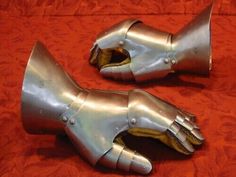 two metal gloves are laying on a red surface