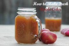 two jars filled with liquid sitting on top of a table next to some fruit and vegetables