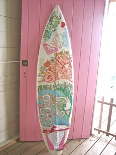 a surfboard is on display in front of a pink door with words written all over it