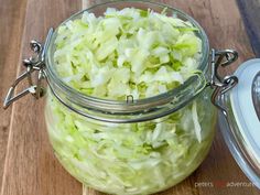 a glass jar filled with chopped cabbage on top of a wooden table