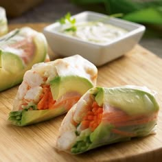 several pieces of food on a wooden board with dipping sauce in the bowl behind them