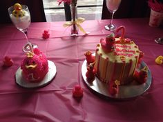 two cakes on plates with pink frosting and decorations