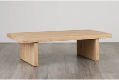 a wooden table sitting on top of a hard wood floor next to a white wall