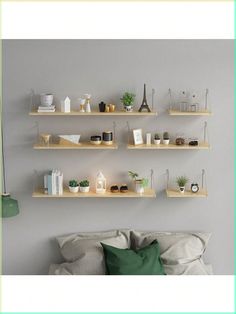 three shelves with plants and other items on them against a gray wall above a bed