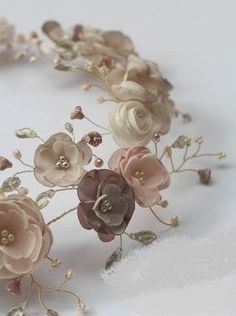 a headband with flowers and pearls is shown on a white surface, close up