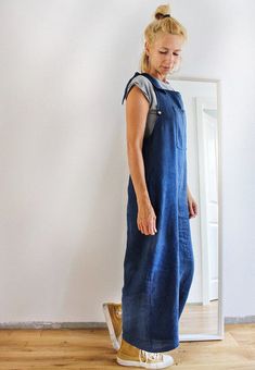 a woman standing in front of a mirror wearing a blue dress and gold booties