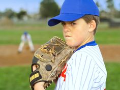 a young boy wearing a catchers mitt on top of a field