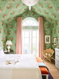 a bedroom with green walls and floral wallpaper on the ceiling, along with white bedding