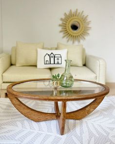 a living room with a couch, coffee table and vase on the floor in front of it