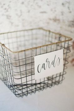 a wire basket with a sign that says cards on it sitting on a white surface