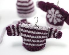 some knitted items are sitting on a white table and one has a hook in it