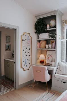 a room with a desk, chair and shelves filled with pictures on the wall next to a window