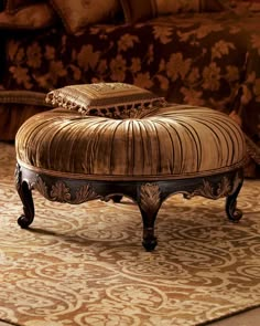 an ornate ottoman sits on top of a rug in front of a couch with pillows