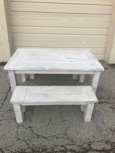 two white benches sitting next to each other in front of a garage door on the sidewalk