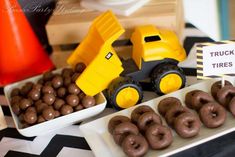 a table topped with chocolate covered donuts and construction trucks