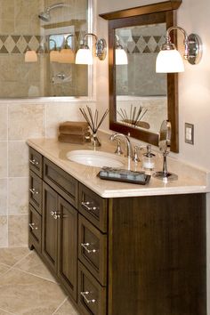 a bathroom with two sinks and a large mirror above the sink is lit by three lights