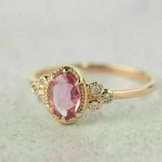 a gold ring with an oval shaped pink stone and two small diamonds on the side