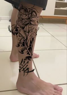 a woman's leg with tattoos on it and an image of a demon in the background