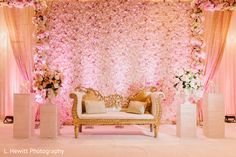 a couch sitting in front of a flower covered wall with pink and white flowers on it