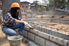 a woman in an orange helmet is working on concrete