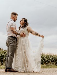 a man and woman standing next to each other in front of a field with corn