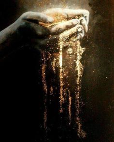 a person holding their hands in the air with gold dust coming out of it's fingers